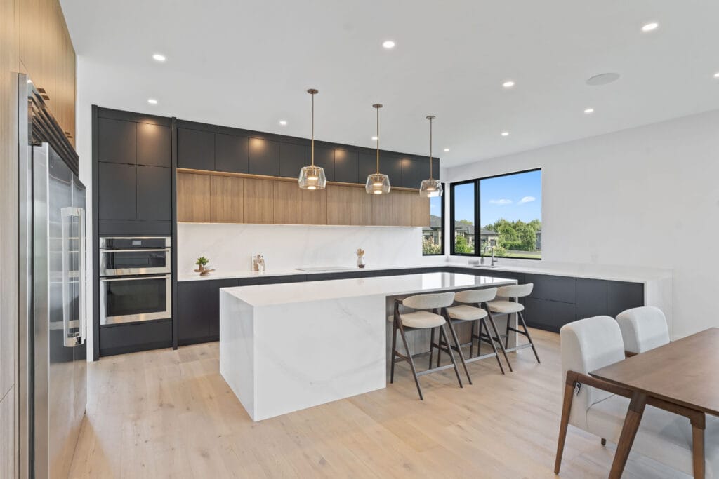Spacious kitchen from Stone Design Concepts portfolio Bespoke Developments Dunblane Project, showcasing a large island, bar seating, and floor-to-ceiling windows for natural light.