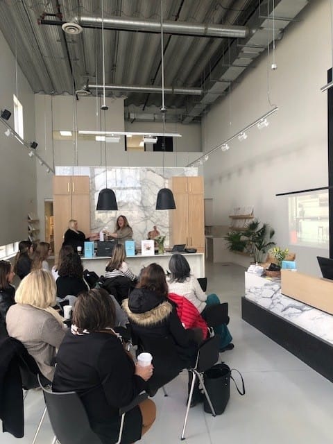 Guests seated and engaged at the Cosentino event Stone Design Concepts, set in a bright, high-ceiling showroom with elegant stone decor elements.