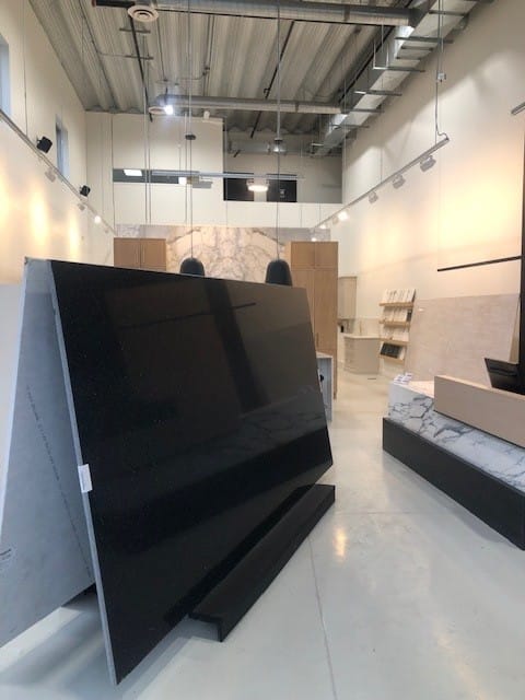 High-gloss black stone slab displayed at the Hanstone colour launch event, surrounded by other stone options and elegant lighting in the showroom.